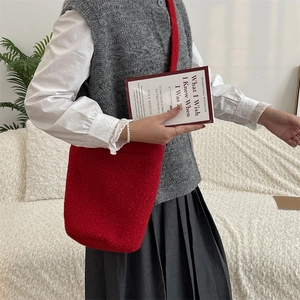 Détail d'un sac seau en peluche rouge porté par un mannequin pour un style automnal