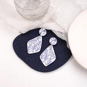 Detail of blue and white floral porcelain style acrylic drop earrings on a velvet pad