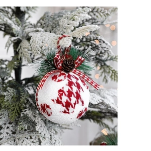Red and white houndstooth Christmas ornaments with pine cones on a snow-covered tree