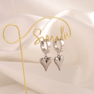 Macro view of silver heart hoop earrings hanging on a stylish golden display stand