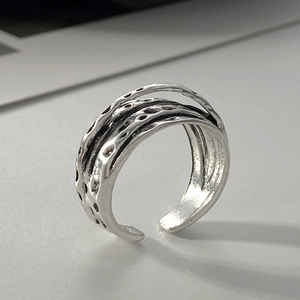 Macro shot of textured silver alloy ring with irregular hammer pattern and open adjustable band