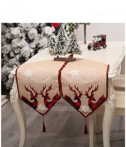 Close-up of burlap Christmas table runner with red reindeer print and tassel detail
