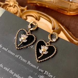 Dettaglio di orecchini a cuore vintage con tulipano in smalto nero e zirconi bianchi