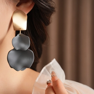 Close-up of matte grey flower petal earrings with gold metal top worn by a model