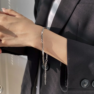 Détail d'un bracelet à maillons géométriques argentés porté avec un fini poli