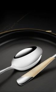 Macro view of stainless steel soup spoon with polished mirror finish and gold honeycomb handle