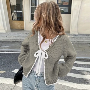 Detail of gray knit cardigan with white wavy lace trim and elegant ribbon bow tie