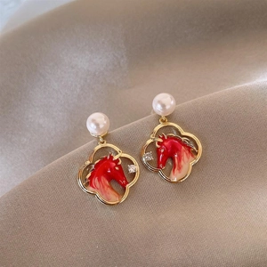 Macro detail of red horse earring with pearl, golden frame and sparkling rhinestone