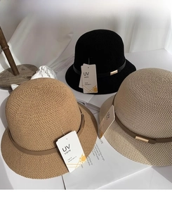Dettaglio di tre cappelli di paglia intrecciati in nero, cammello e beige con cinturino