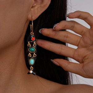 Detailed close-up of C-shaped fish earrings with colorful stones and black enamel