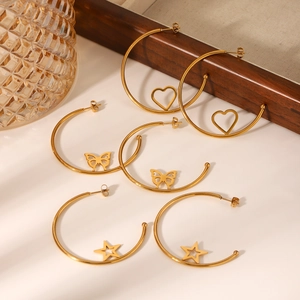 Detail of gold C-shaped hoop earrings with heart, butterfly, and star pendants