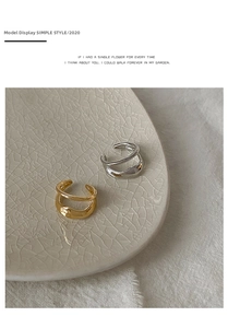 Minimalist double-layer C-shaped gold and silver ear cuffs on a ceramic tray