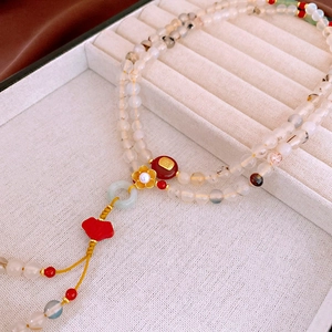 Close-up of a Neo-Chinese floral pearl and agate bead necklace on a jewelry display box