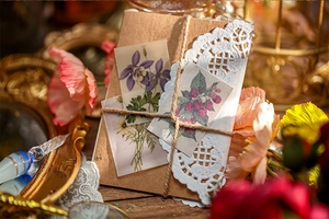 Detail of vintage kraft envelope with lace trim, hemp rope, and floral stickers