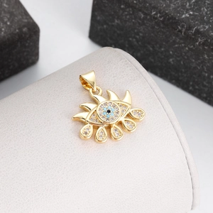 Detailed close-up of a gold evil eye pendant with sparkling blue and clear crystals