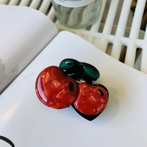 Vintage acetate cherry hair claw clip with pearlescent finish on a white book
