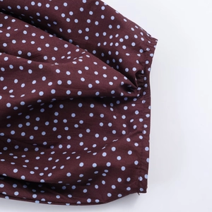 Detail of dark brown blouse with light blue polka dots and precision stitching