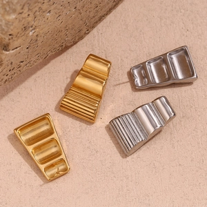 Macro detail of geometric trapezoid stud earrings with textured ridges on stone surface