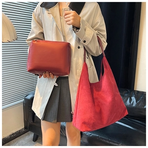 Detail of dark red faux suede tote bag set with matching zipper pouch on a leather sofa
