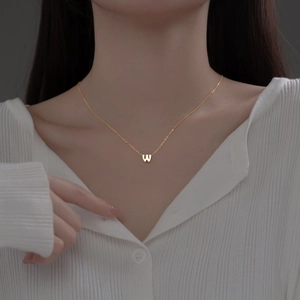 Elegant gold S925 sterling silver necklace featuring a letter W pendant on a model