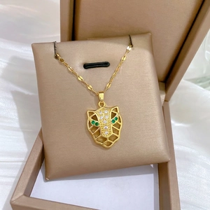 Gold leopard head pendant necklace with green eyes and white zircons on a wavy chain