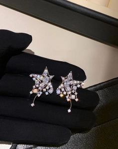 Macro detail of silver star drop earrings with sparkling cubic zirconia on a dark glove