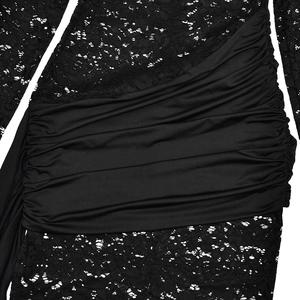 Detail view of black dress showing intricate floral lace texture and pleated patchwork fabric
