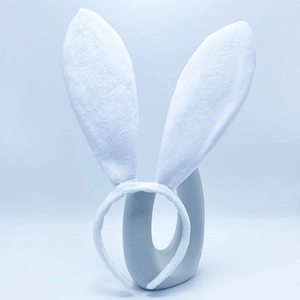 Close-up of a white plush rabbit ear headband on a sleek ceramic stand for party decor