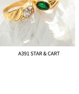 Detail of gold rings with wavy texture featuring green emerald and clear zircon gems