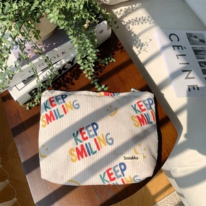 Detail of off-white corduroy organizer bag with Keep Smiling letters on a wooden chair