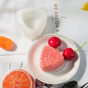 Macro-opname van een driehoekige siliconen cakevorm met getextureerde wanden en roze mousse