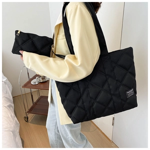 Detail of black quilted nylon tote bag with matching pouch shown on a model
