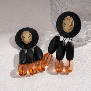 Detail of vintage earrings featuring gold cameo portraits and acrylic beads