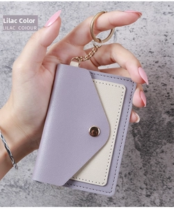 Detailed close-up of a lilac and cream leather card holder with golden keychain attachment