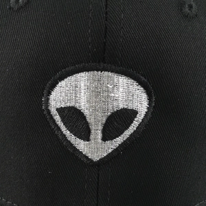 Vue de face de la casquette noire avec broderie tête d'alien argentée sur tissu sergé