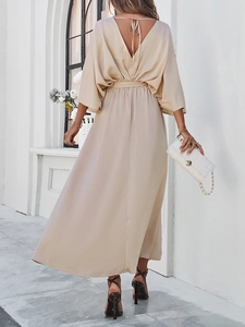 Detail of elegant beige V-neck dress showing waist tie and silk-like fabric texture from behind
