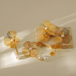 3D metallic gold floral earrings with hanging pearl tassels on a minimalist stone base