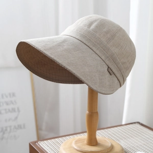 Detail of beige linen sun hat with wide brim showing fine fabric texture and brown label