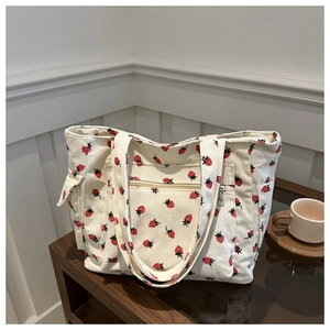 Beige corduroy handbag with strawberry pattern on a wooden table for daily casual use