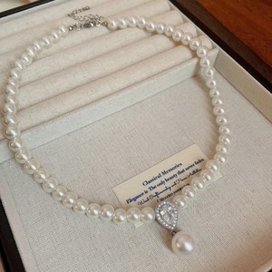 Detailed view of irregular pearl necklace with pear-cut stone and teardrop pearl pendant