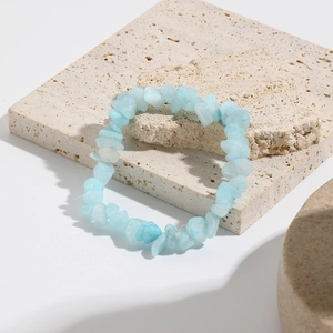 Close-up of light blue natural crushed stone stretch bracelet on beige stone slab