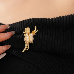 Close-up of a gold-plated pegasus brooch with cubic zirconia on black knitwear