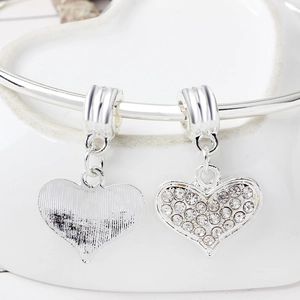 Detailed view of silver heart charms with inset rhinestones for DIY jewelry making