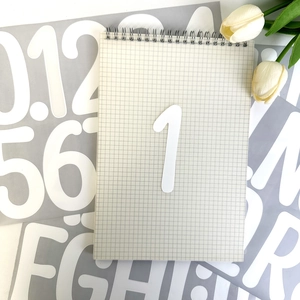 Détail d'autocollant chiffre en vinyle blanc de 4 pouces sur un carnet avec fleurs