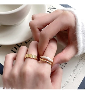 Detail of elegant gold-plated layered rings with shell inlay and textured band