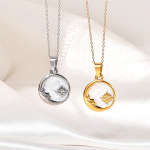 Detail of silver and gold moon star necklaces on white silk featuring shell inlay
