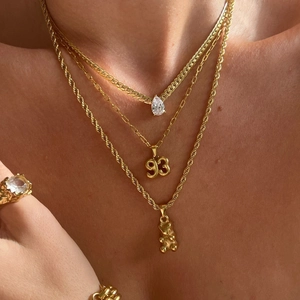 Layered gold necklaces with 93 year number pendant, bear charm and sparkling zircon ring