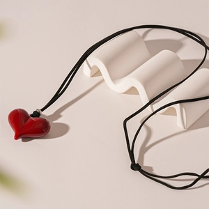 Close-up of red resin heart pendant with black adjustable cord on stone prop
