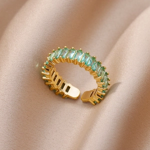 Macro view of adjustable gold ring with emerald green rectangular zircon on champagne satin