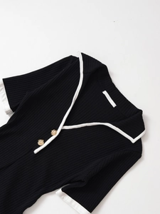 Dettaglio dell'abito in maglia con scollo a V, bordi a contrasto e bottoni dorati